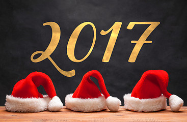 Image showing The three Santa red hats on wooden background