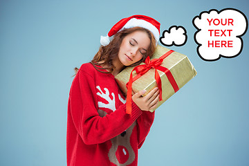 Image showing Girl dressed in santa hat with a Christmas gift