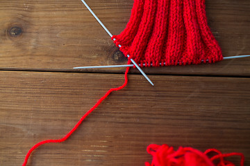 Image showing hand-knitted item with knitting needles on wood