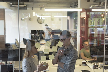 Image showing young couple at modern office interior writing notes on stickers