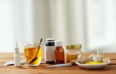 Image showing drugs, thermometer, honey and cup of tea on wood