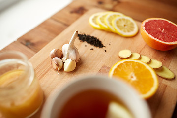 Image showing ginger tea with honey, citrus and garlic on wood