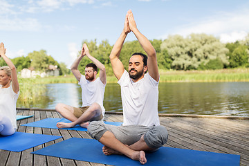 Image showing people meditating in yoga lotus pose outdoors