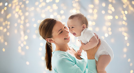 Image showing happy young mother with little baby over lights