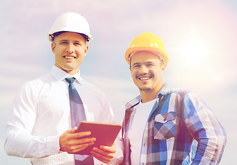 Image showing smiling builders in hardhats with tablet pc