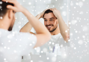 Image showing happy young man looking to mirror at home bathroom