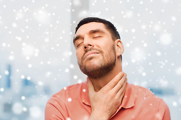 Image showing unhappy man suffering from throat pain over snow