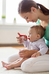 Image showing happy mother with spoon feeding baby at home