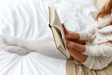 Image showing close up of young woman reading book in bed