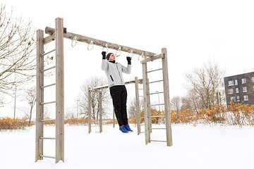 Image showing young man exercising on horizontal bar in winter