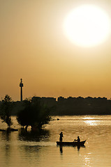 Image showing silhouette of fishermen with and orange sun 