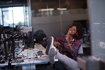 Image showing woman at her workplace in startup business office listening musi