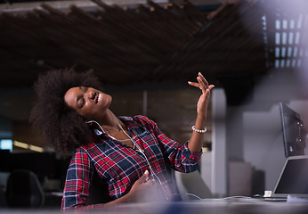 Image showing woman at her workplace in startup business office listening musi