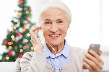 Image showing senior woman with smartphone and earphones at home