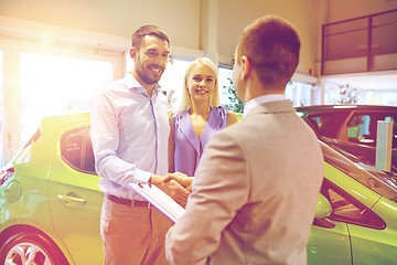 Image showing happy couple with car dealer in auto show or salon