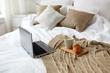 Image showing laptop, coffee and croissant on bed at cozy home