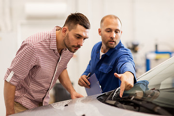 Image showing auto mechanic with clipboard and man at car shop