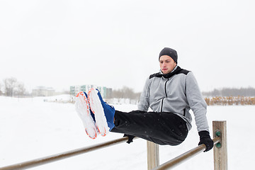 Image showing young man exercising on parallel bars in winter