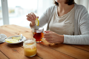 Image showing close up of woman adding lemon to tea cup