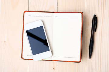 Image showing Small notepad with pen and smartphone