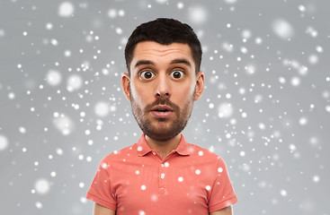 Image showing surprised man in polo t-shirt over snow background