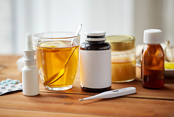 Image showing drugs, thermometer, honey and cup of tea on wood