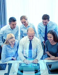 Image showing smiling business people with laptop in office