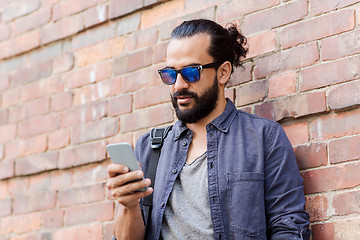 Image showing man with backpack texting on smartphone in city