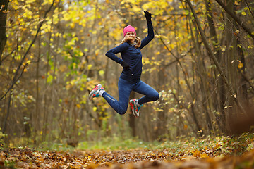 Image showing Sportswoman running among autumn leaves