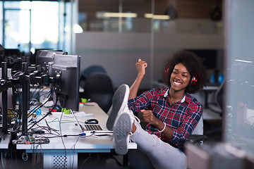 Image showing woman at her workplace in startup business office listening musi