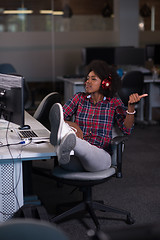 Image showing woman at her workplace in startup business office listening musi