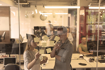 Image showing young couple at modern office interior writing notes on stickers