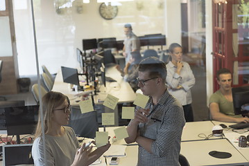 Image showing young couple at modern office interior writing notes on stickers