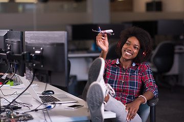 Image showing young woman at her office workplace playing with plane toy