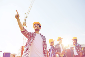 Image showing group of smiling builders in hardhats outdoors