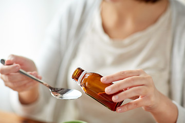 Image showing woman pouring medicine from bottle to spoon