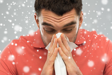 Image showing sick man with paper wipe blowing nose over snow
