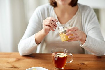 Image showing close up of ill woman drinking tea with honey