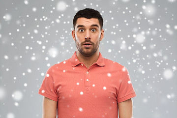 Image showing surprised man in polo t-shirt over snow background