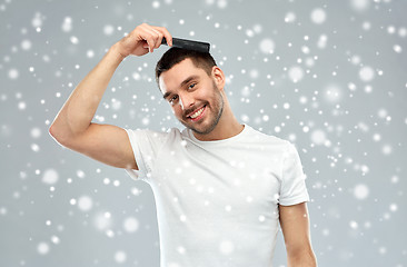 Image showing happy man brushing hair with comb over snow