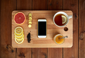 Image showing smartphone with cup of lemon tea, honey and ginger