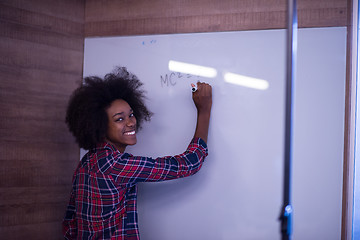 Image showing black  woman writing on a white board  in a modern office