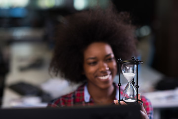 Image showing young woman at office looking at sand  clock