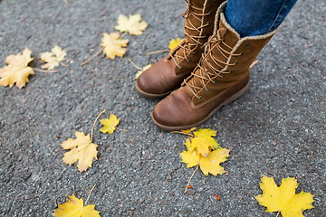 Image showing female feet in boots and autumn leaves