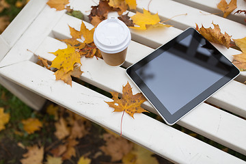 Image showing tablet pc and coffee cup on bench in autumn park