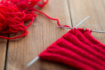 Image showing hand-knitted item with knitting needles on wood