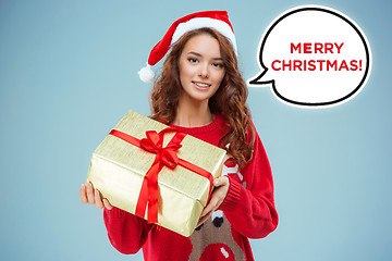 Image showing Girl dressed in santa hat with a Christmas gift