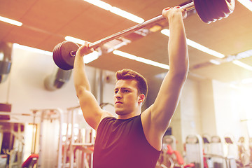 Image showing young man flexing muscles with barbell in gym