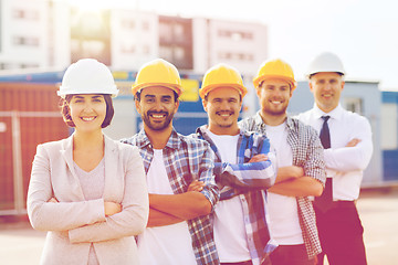 Image showing group of smiling builders in hardhats outdoors