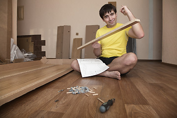 Image showing Young man assembling furniture